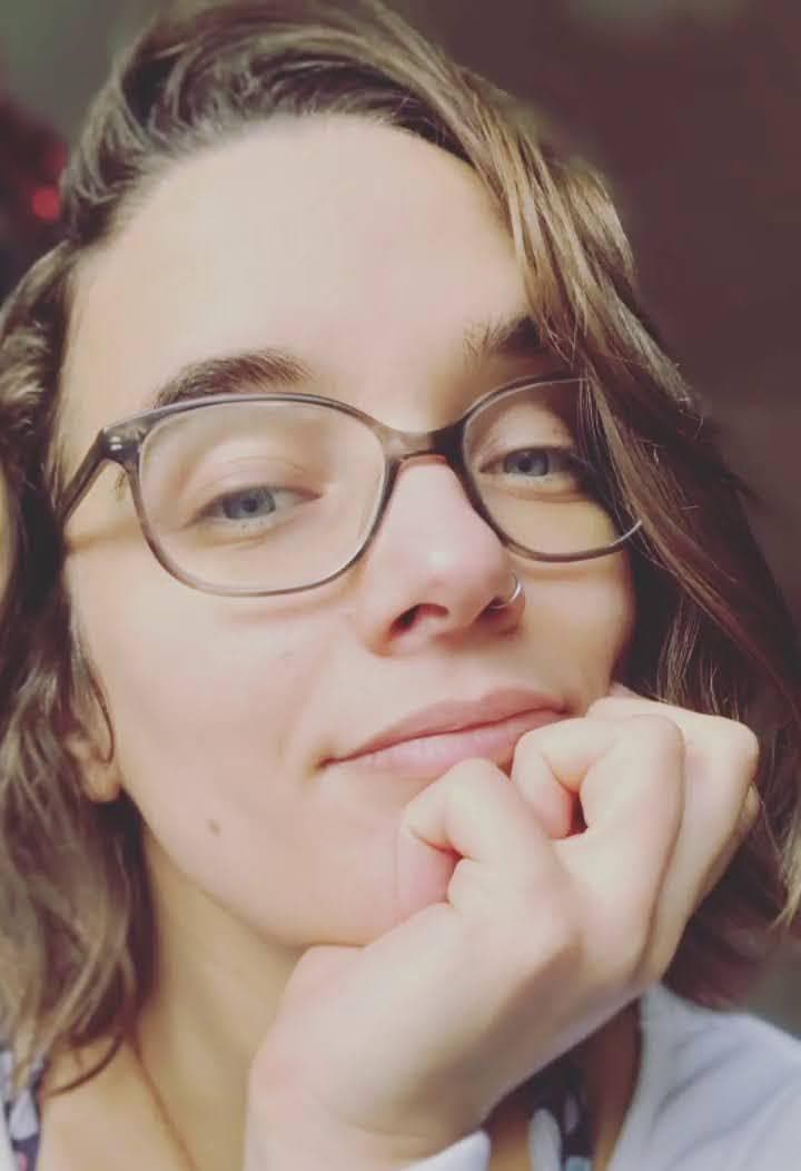 Portrait rapproché de Clémence, le menton posé sur les mains, le regard vers l’objectif.